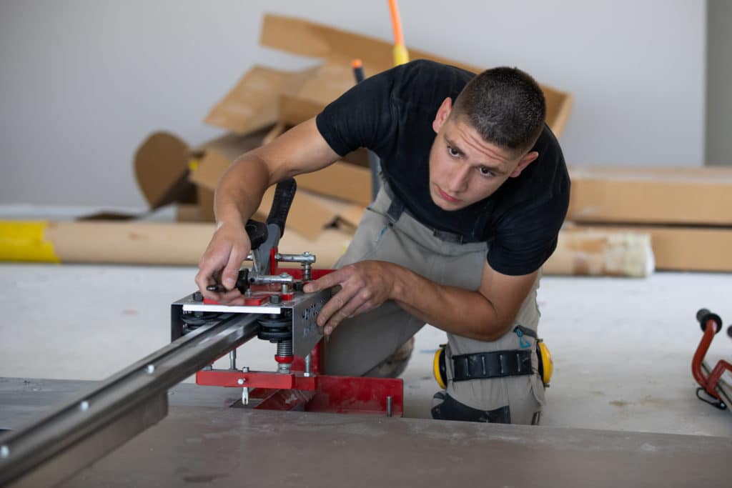 Apprenti carreleur utilisant machine de découpe carrelage grand format