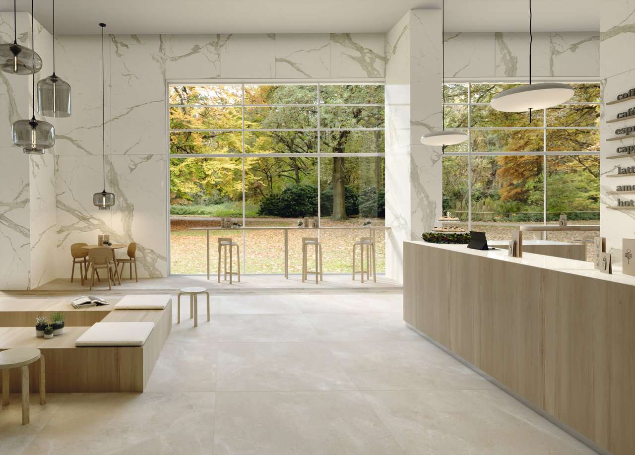 Salle de restaurant avec baie vitrée et mur en carrelage imitation marbre Calacatta blanc